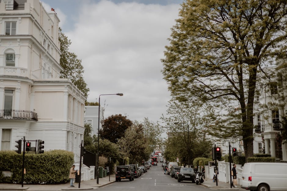 A wide view of a residential street in Lisson Grove during daytime, featuring white Victorian-style townhouses with ornate architectural details and balconies on the left side, and similar buildings o