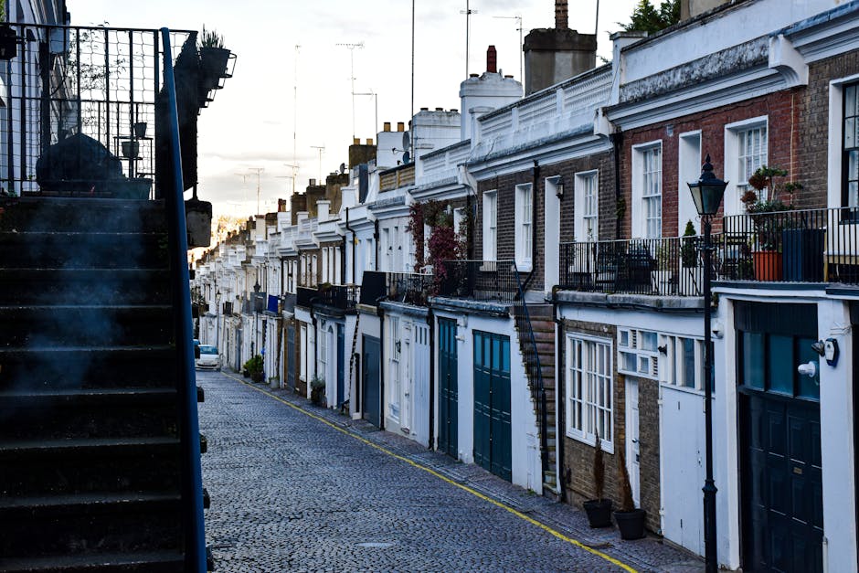 A wide view of a residential street in Lisson Grove during daytime, featuring white Victorian-style townhouses with ornate architectural details and balconies on the left side, and similar buildings o